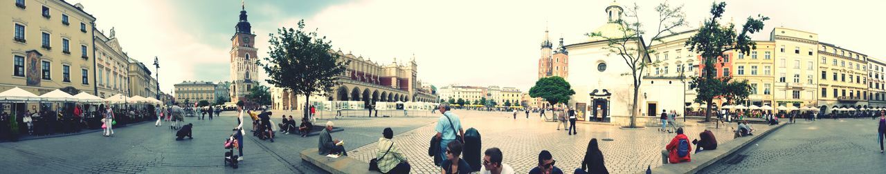 building exterior, architecture, built structure, large group of people, street, city, person, city life, men, city street, lifestyles, walking, road, mixed age range, town square, street light, transportation, sky, crowd