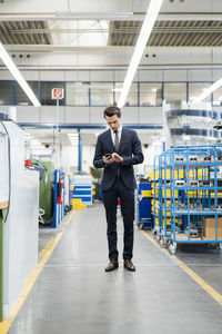 Businessman using cell phone in a factory