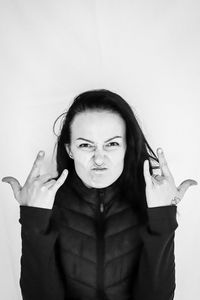 Portrait of young woman standing against white background