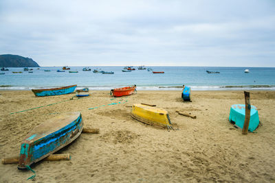 Deck chairs on beach against sky