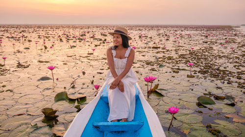 Portrait of young woman sitting on pier at beach