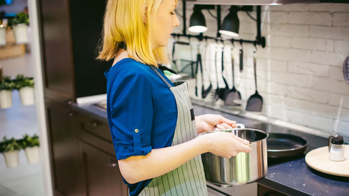 Side view of young woman working in kitchen