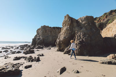 Mid adult woman walking by rock formations at beach