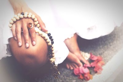 Low section of woman holding bead necklace