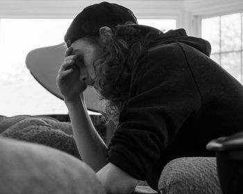 Side view of man sitting on sofa at home