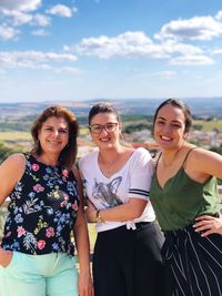 Portrait of smiling friends standing against sky