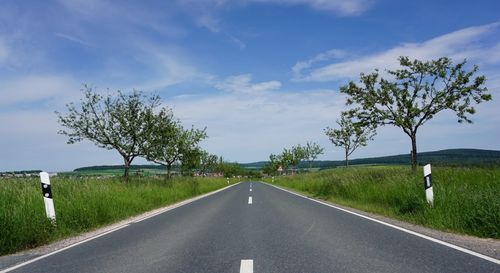 Road amidst green landscape against sky