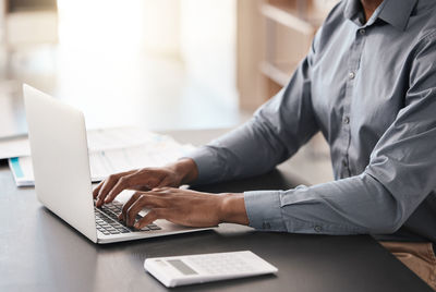 Midsection of man using laptop at office