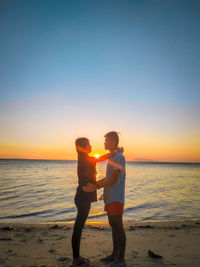 Man standing on beach against sea during sunset