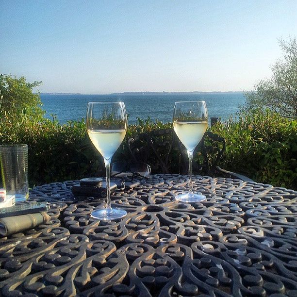 water, sea, clear sky, drink, horizon over water, food and drink, beach, blue, refreshment, table, copy space, drinking glass, tranquil scene, sky, tranquility, freshness, scenics, sunlight, nature, still life