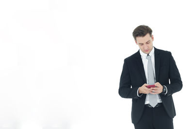 Young man using smart phone against white background