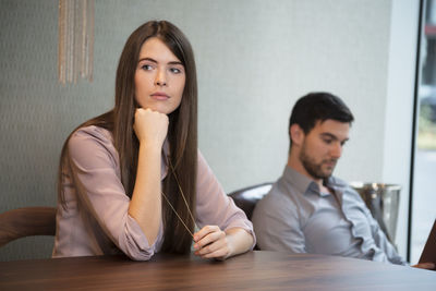 Thoughtful young woman with man in background