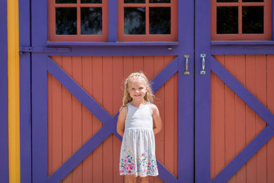 Portrait of smiling girl standing against door