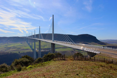 Suspension bridge over mountain against sky