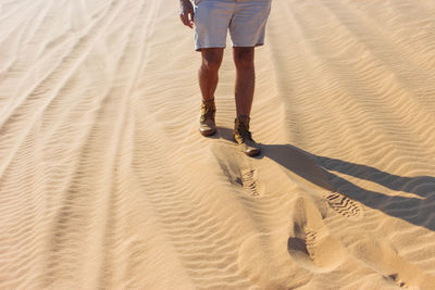 Low section of woman walking on sand at beach