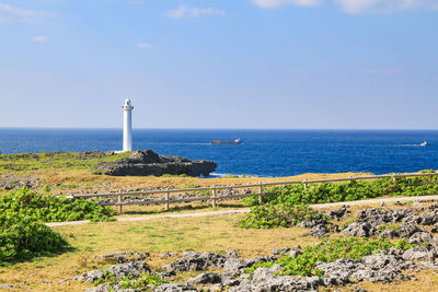 Lighthouse by sea against sky