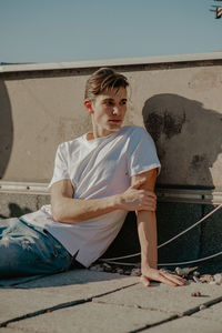 Full length of young man sitting against wall