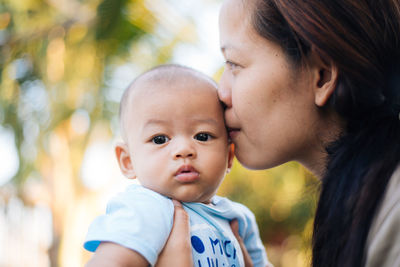 Mother kissing baby boy in park