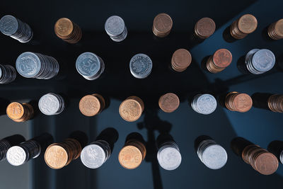 Piles of coins on a black, reflective surface seen from the top. inflation consuming our savings. 