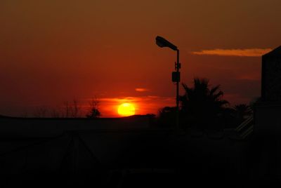 Silhouette street light against orange sky