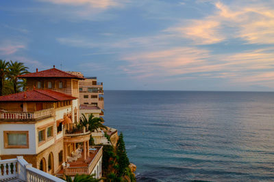 Building by sea against sky during sunset