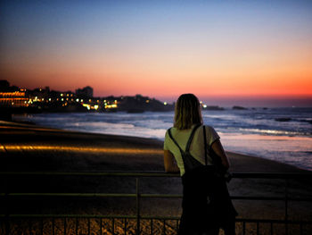 Rear view of woman looking at beach during sunset