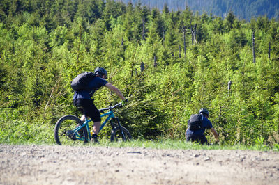 Man riding bicycle on street amidst trees