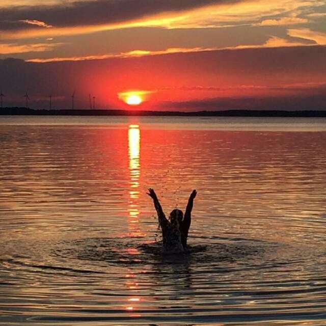 sunset, water, reflection, silhouette, sun, sea, orange color, rippled, scenics, tranquility, beauty in nature, tranquil scene, nature, waterfront, romantic sky, sky, cloud - sky, outline, atmosphere, dramatic sky, swimming, enjoyment, calm, splashing, moody sky, back lit, carefree, atmospheric mood