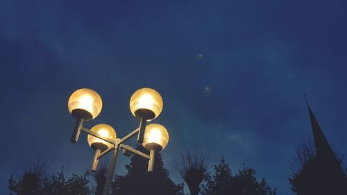 Low angle view of illuminated street light against blue sky