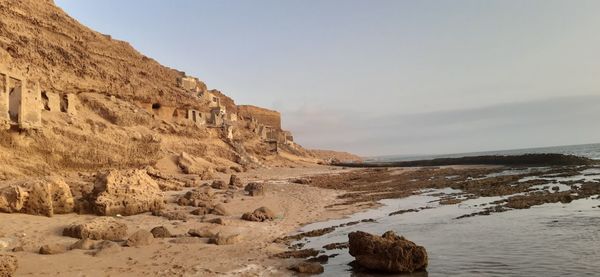 Rock formations on shore against sky