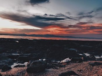 Scenic view of sea against cloudy sky during sunset