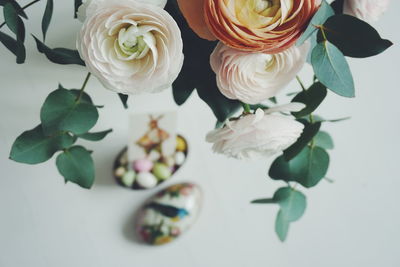 High angle view of ranunculus against easter eggs against over white background