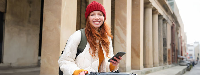 Portrait of young woman standing against wall