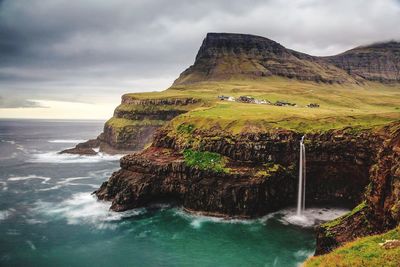 Scenic view of sea by cliff against sky