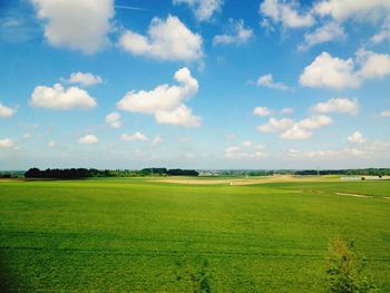 Scenic view of green landscape against cloudy blue sky
