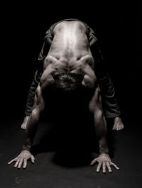 Young man bending against black background