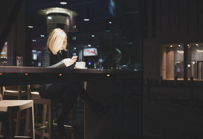 Woman using phone in cafe