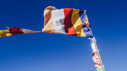 Low angle view of flag against clear blue sky on sunny day