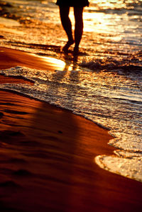 Low section of silhouette people walking on beach