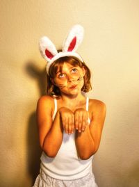 Girl in bunny costume standing against wall