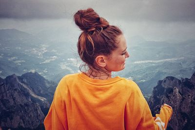 Rear view of woman looking at mountains against sky