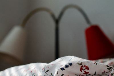 Close-up of bedsheet by lamp in bedroom