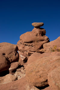 Low angle view of rock formations against clear blue sky
