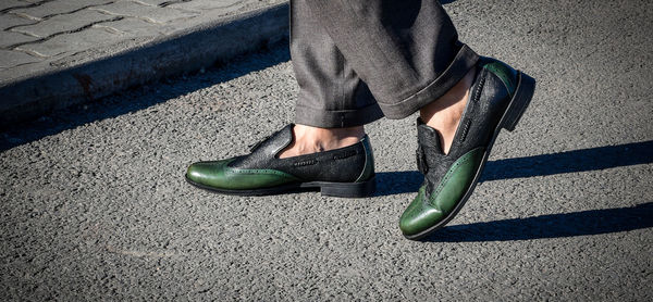 Low section of man wearing shoes standing on street