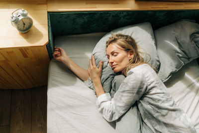 Lifestyle portrait of a woman in pajamas sleeping while lying in bed blissfully.