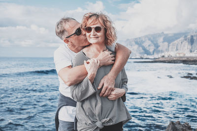 Portrait of young woman wearing sunglasses while standing against sea