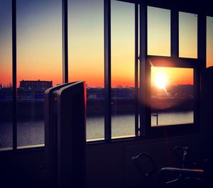 View of cityscape through window during sunset