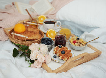 Romantic breakfast with coffee, waffles, orange juice and rose flowers.