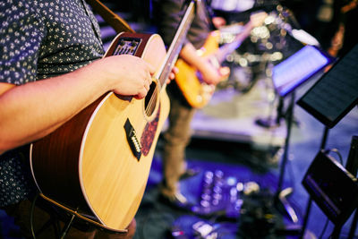 Midsection of musician playing guitar on stage