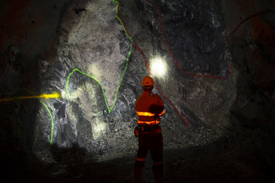 Rear view of worker standing in cave